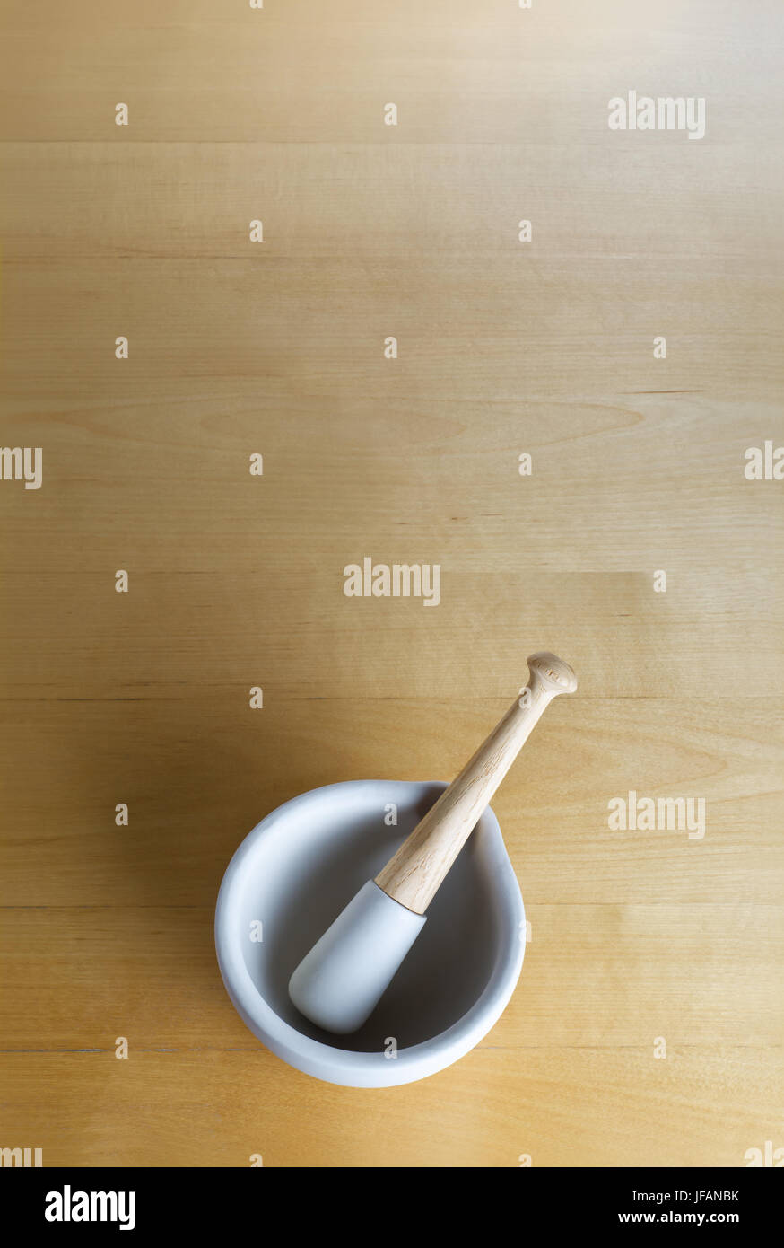 overhead shot of a pestle and mortar, centred lower frame on a wooden surface which provides generous copy space above. Stock Photo