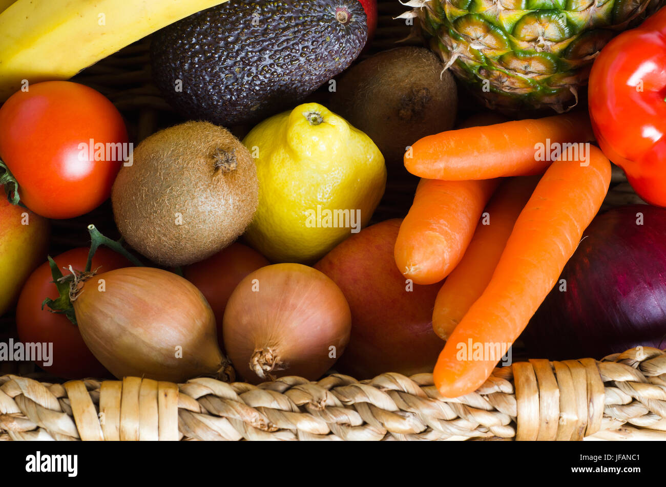 Overhead shot of a basket crammed with raw, fresh, colourful fruit and vegetables.  Landscape orientation. Stock Photo