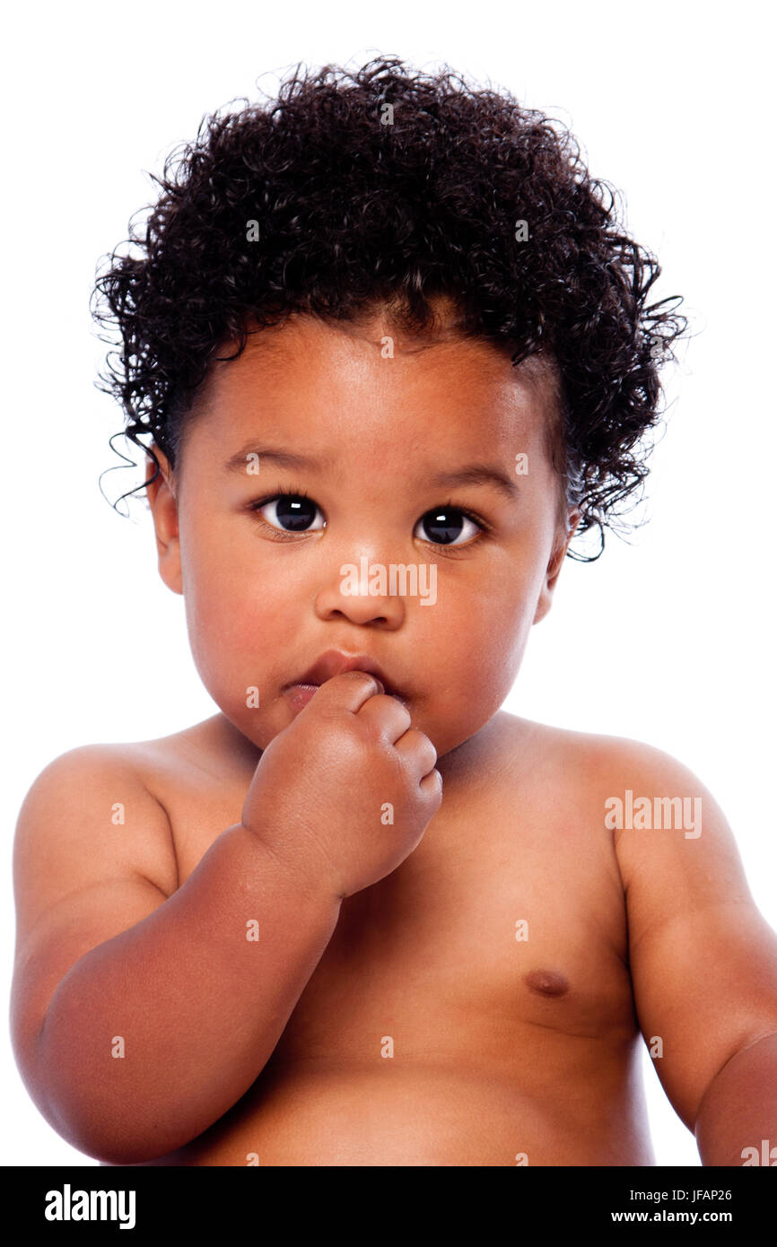 Cute adorable beautiful baby toddler face with hand in mouth and innocent expression and curly hair. Stock Photo