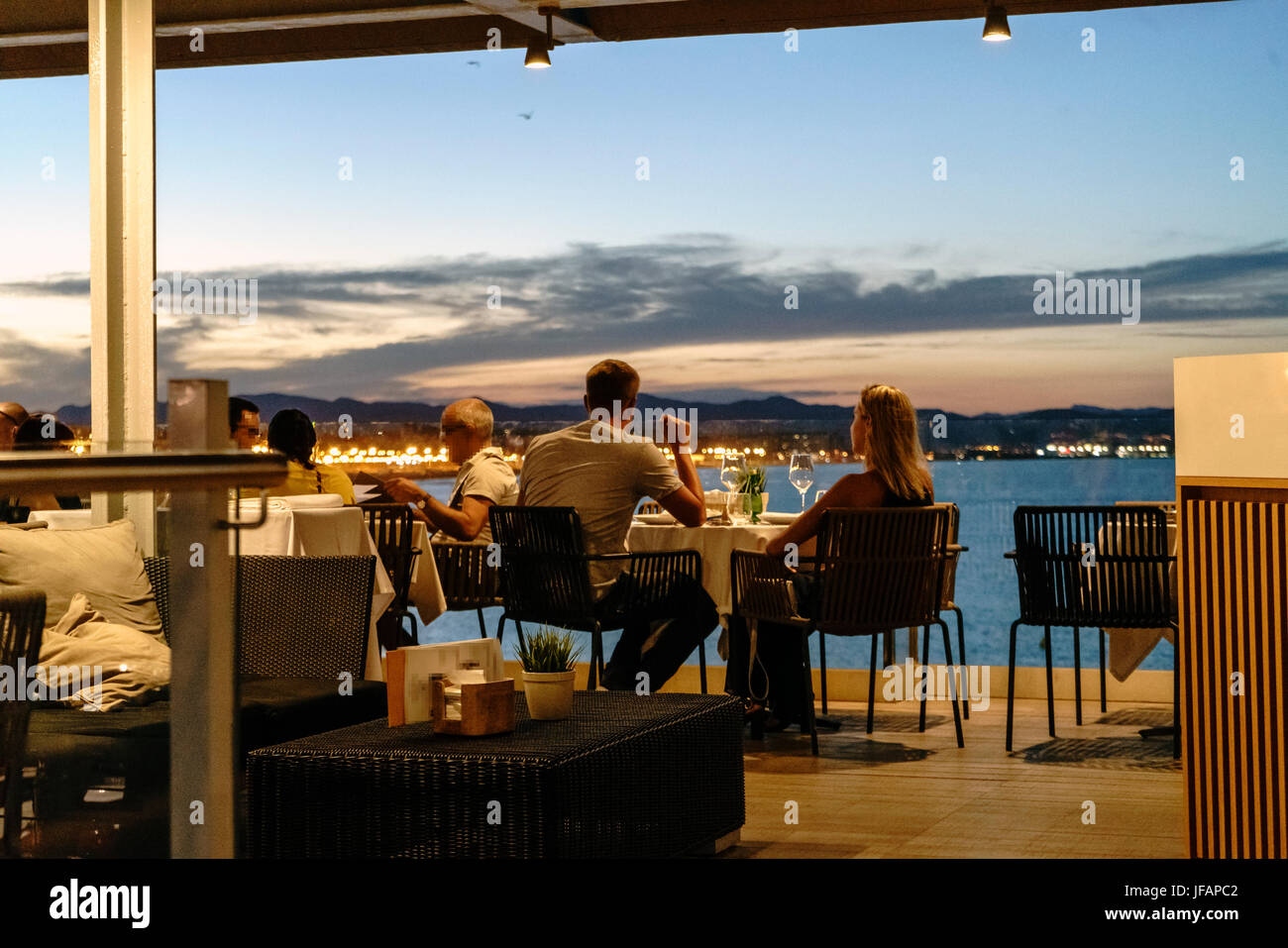 Young couple having dinner at a restaurant by the sea at night Stock