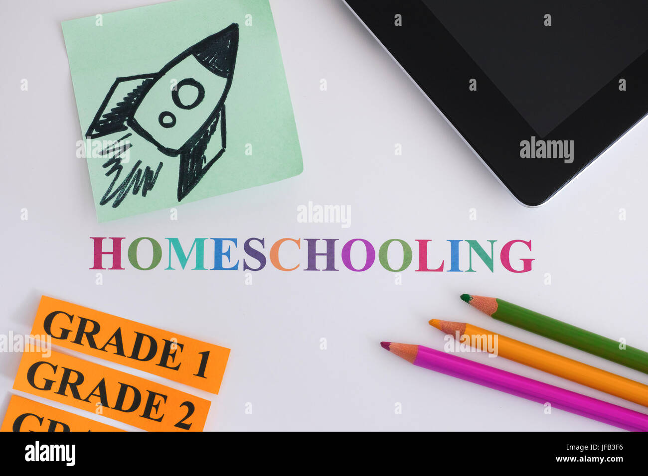 Homeschooling. Digital tablet, pencils and paper notes with a rocket on it. Homeschooling concept image. The education of children at home by their pa Stock Photo