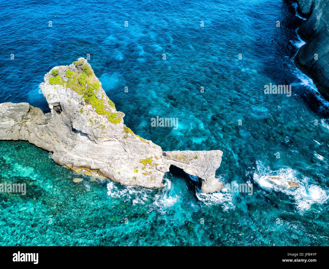 Dramatic aerial view of the coral reef surrounding the natural arch near Atuh Beach on Nusa Penida, Bali, Indonesia. Stock Photo