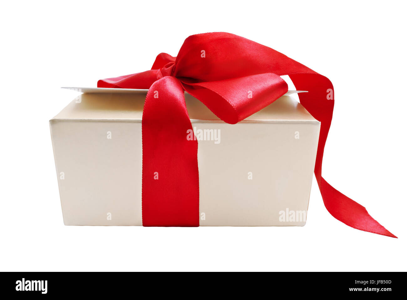 A gold gift box with tied red ribbon trailing onto the ground, isolated on white background. Stock Photo