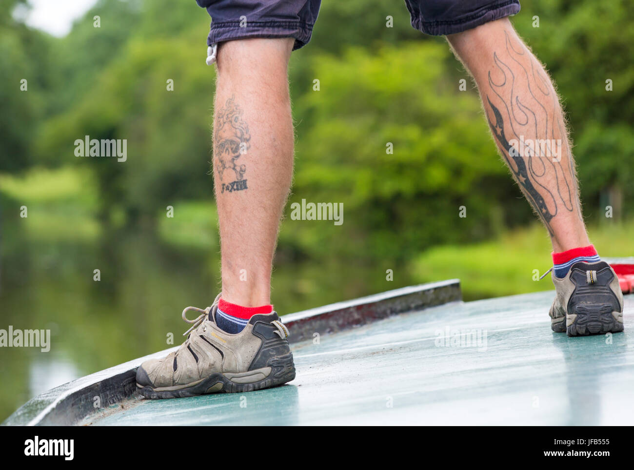 tattoos on legs on man standing on barge Stock Photo