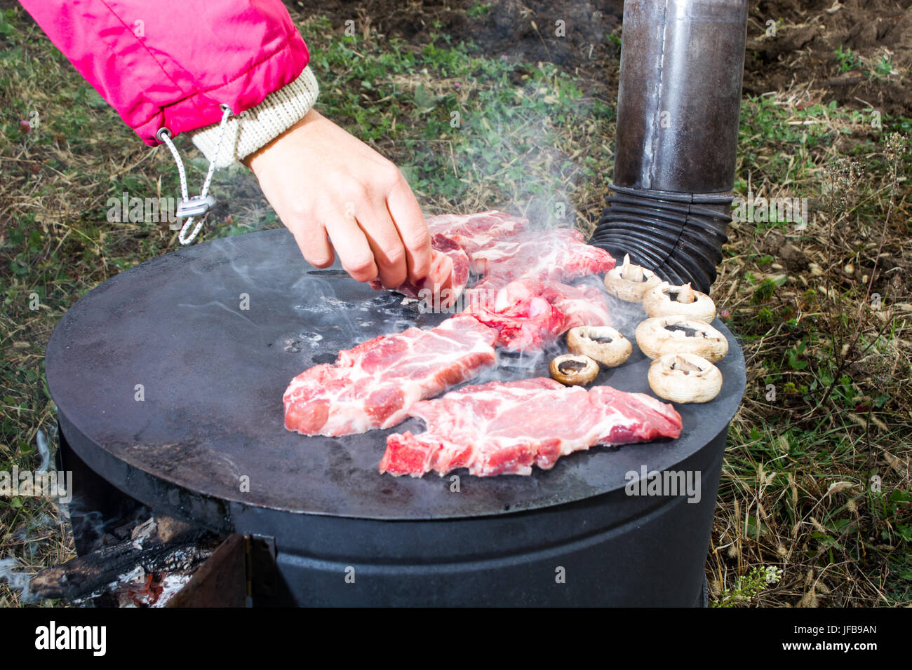 Grilling meat on wood stove Stock Photo Alamy