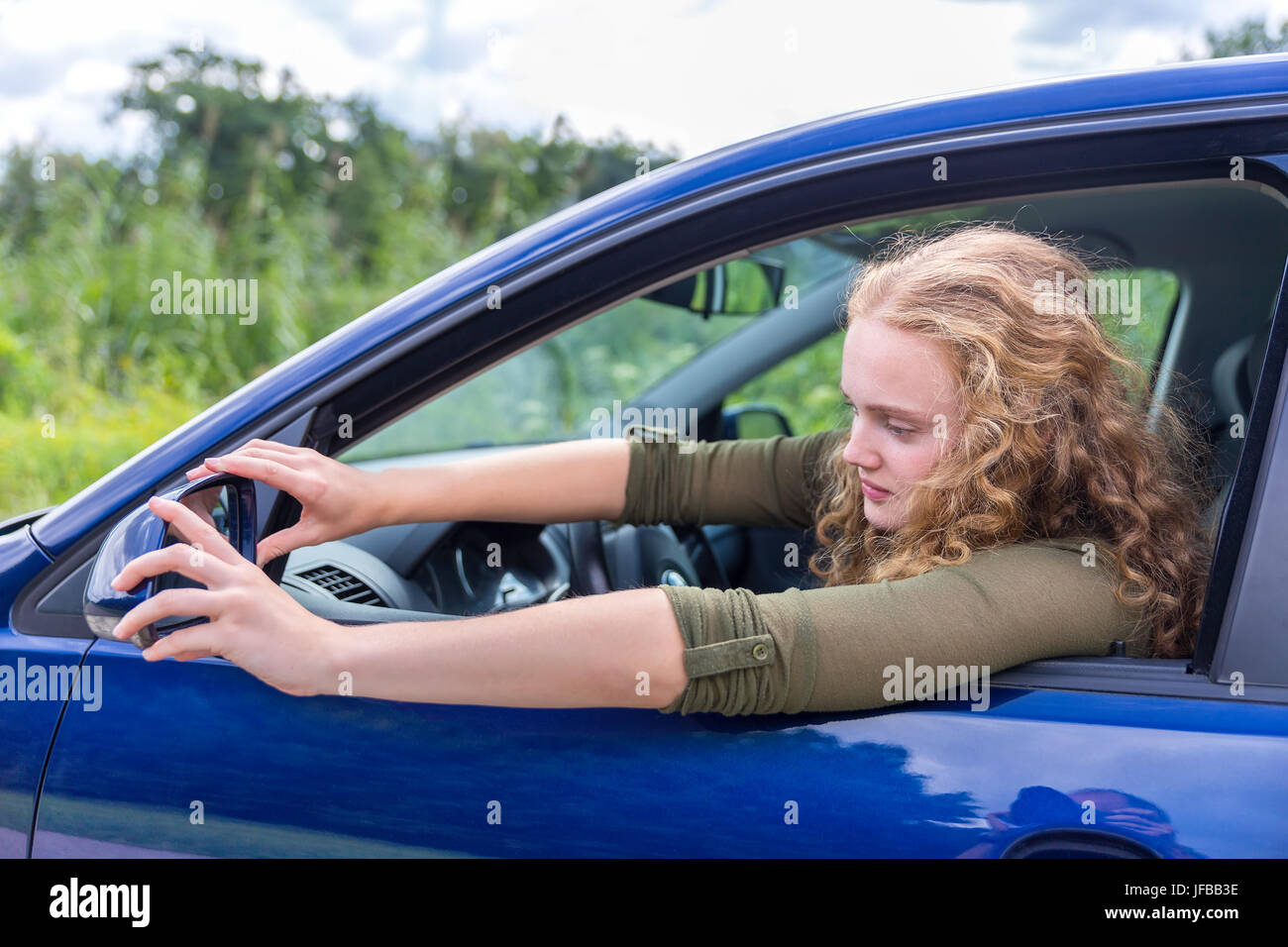 Caucasian woman adjusting side mirror of car Stock Photo