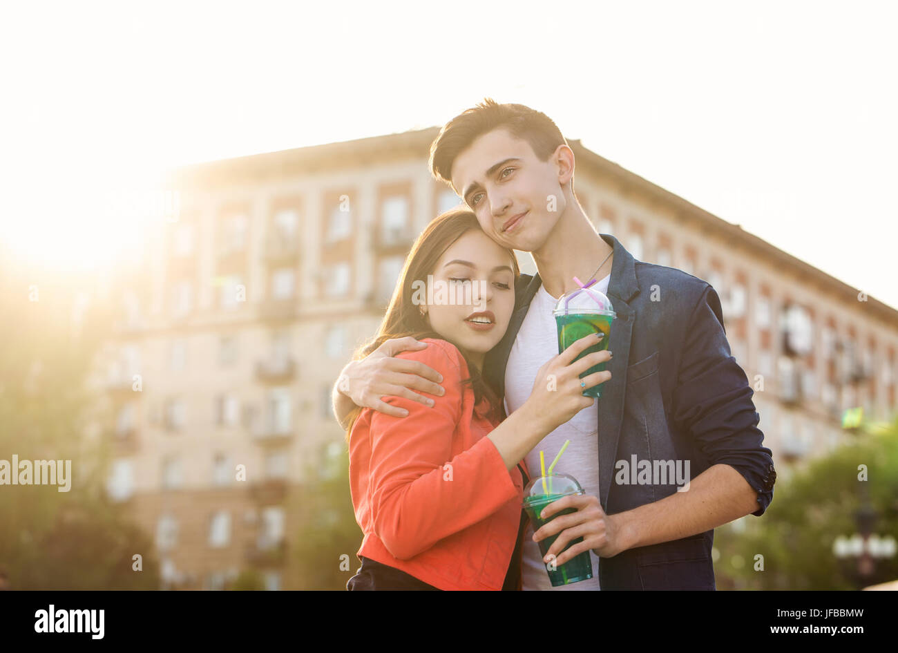 Teenagers drink fruit fresh from glasses. They embrace. A couple in love on a date. Romance of first love. Stock Photo