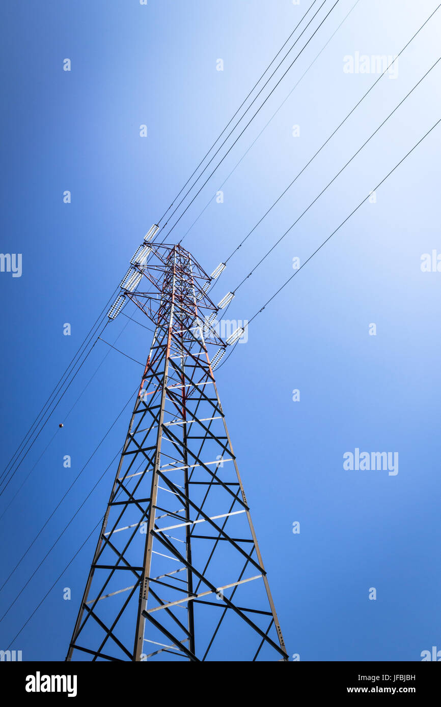 Overhead power line and a pylon against the blue sky Stock Photo
