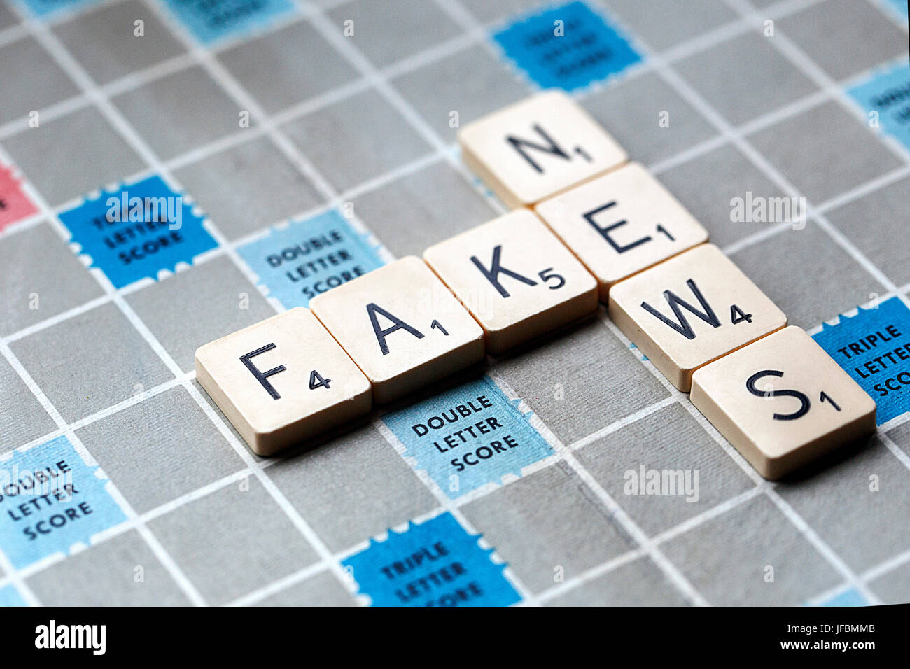 A Scrabble game board with the letters forming the words 'Fake News'. Scrabble is a fun and educational game distributed worldwide by Hasbro. Stock Photo