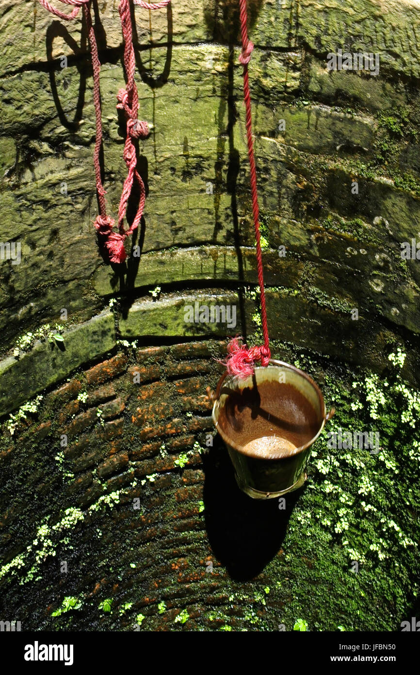 A bucket hangs in a public water well. Stock Photo