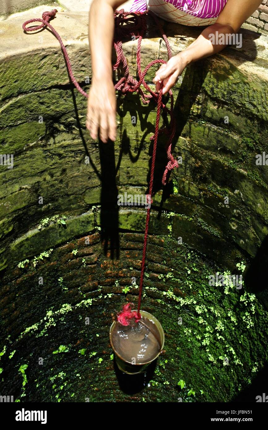 A woman pulls clean water from a water well. Stock Photo