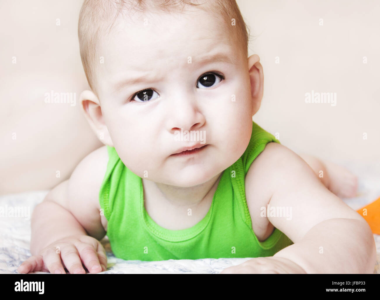 baby staring in bed with curious eyes looking around lying down Stock Photo