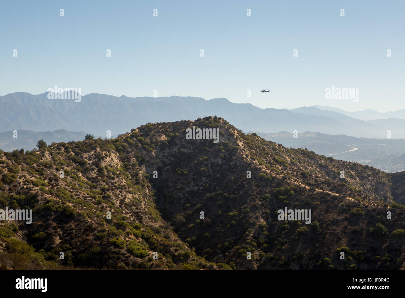 A helicopter flies over the hills outside of Los Angeles and Hollywood near Griffith Observatory. Stock Photo
