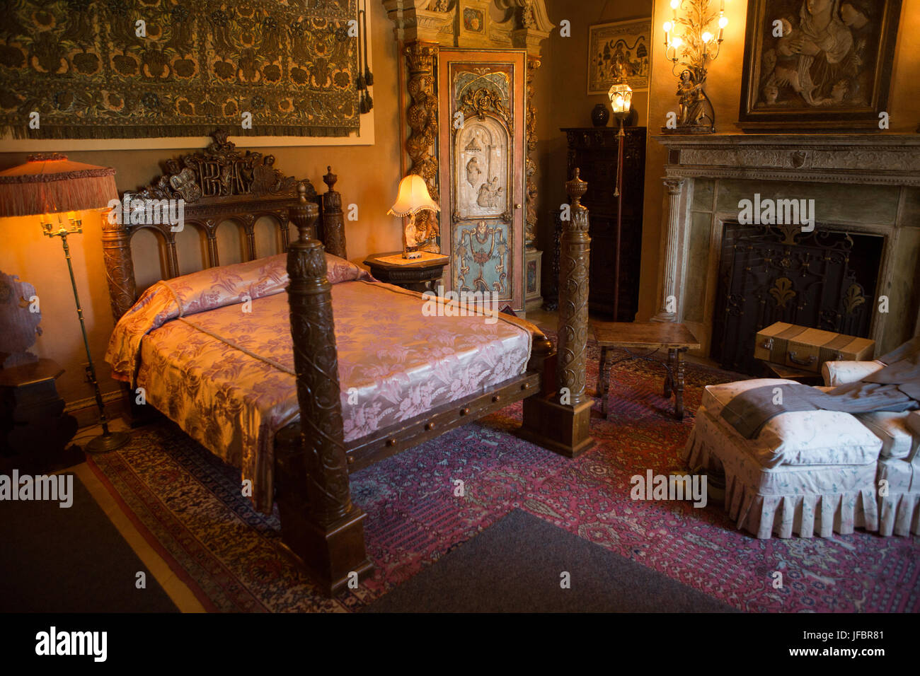 A bedroom decorated with furniture, tapestries, artwork and ornate light fixtures. Stock Photo