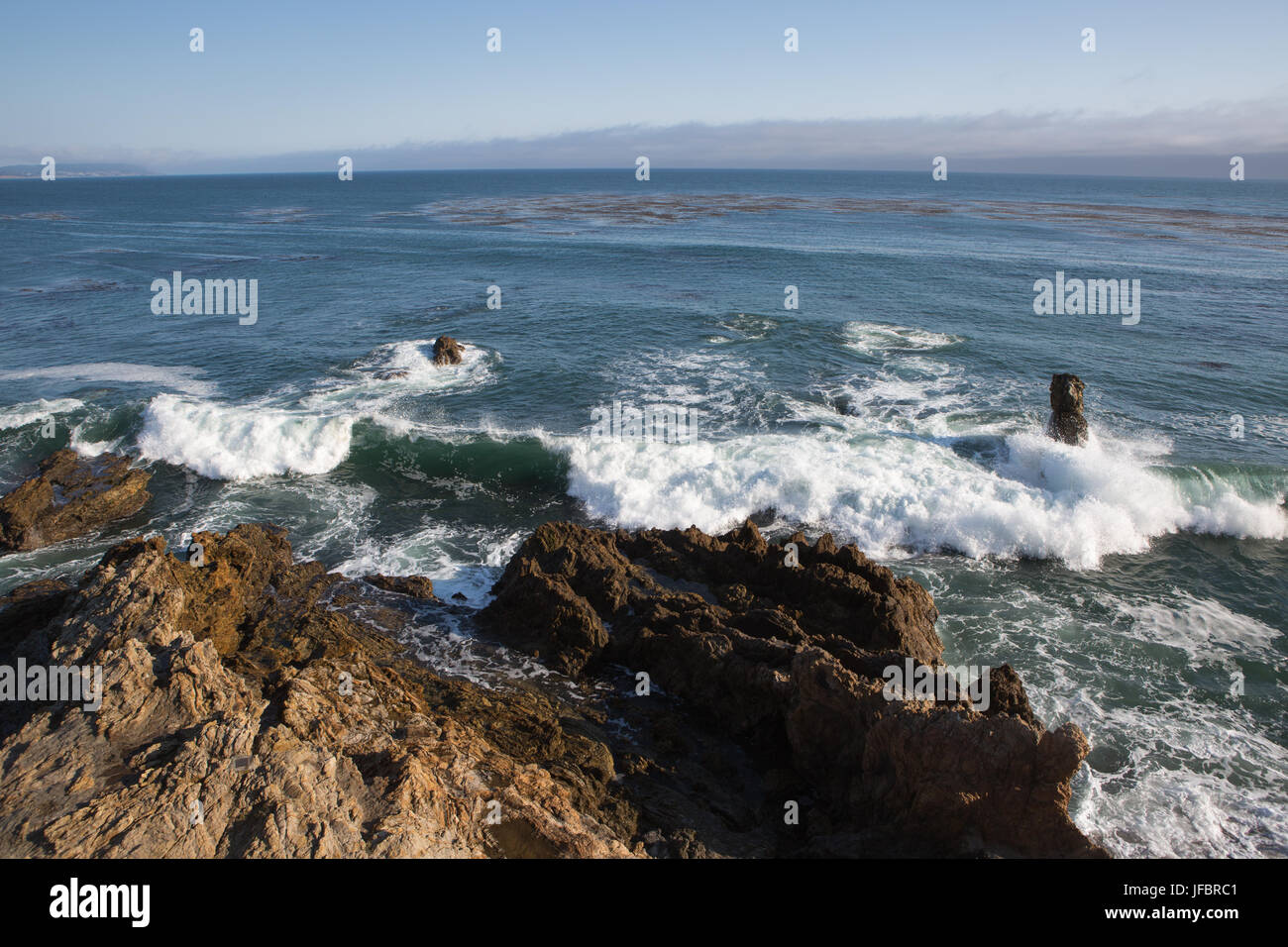 Waves crash onto rock formations on a Pacific coast. Stock Photo