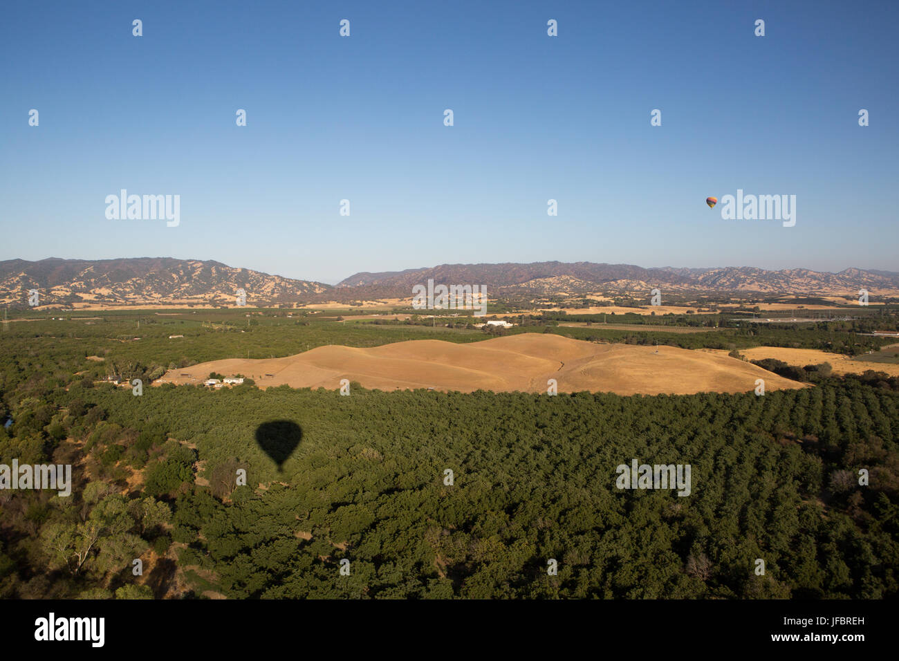 Hot air balloons fly over agricultural fields and vineyards in California, east of Napa Valley. Stock Photo