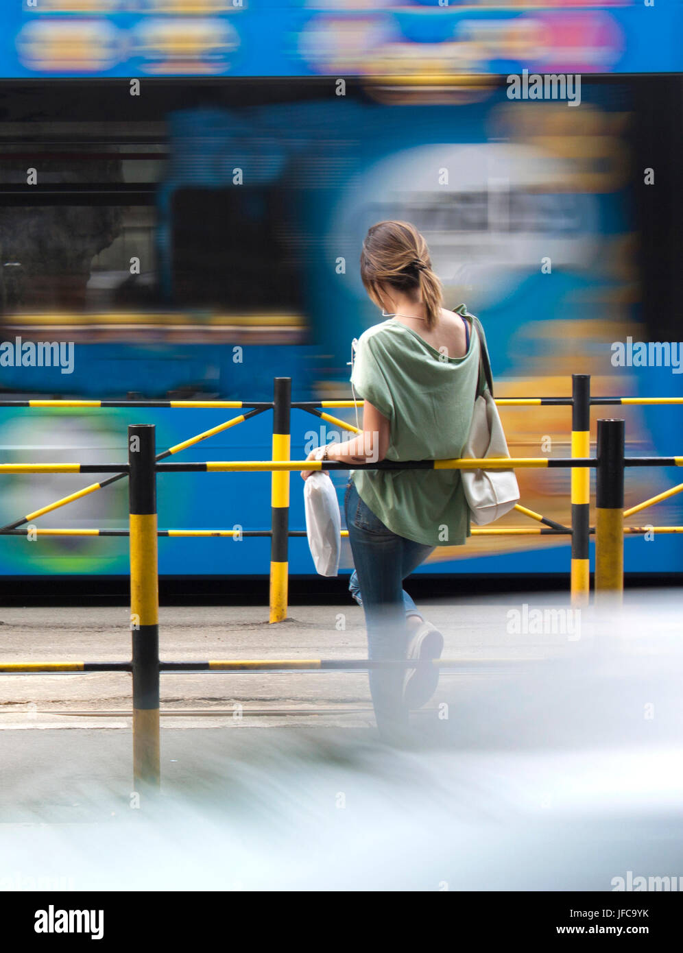 One young woman waiting for public transport at bus stop Stock Photo