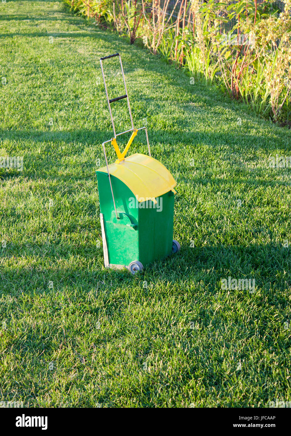 Outdoor small trolley litter bin dustpan with long handle  from city cleaning service in the park grass lawn Stock Photo