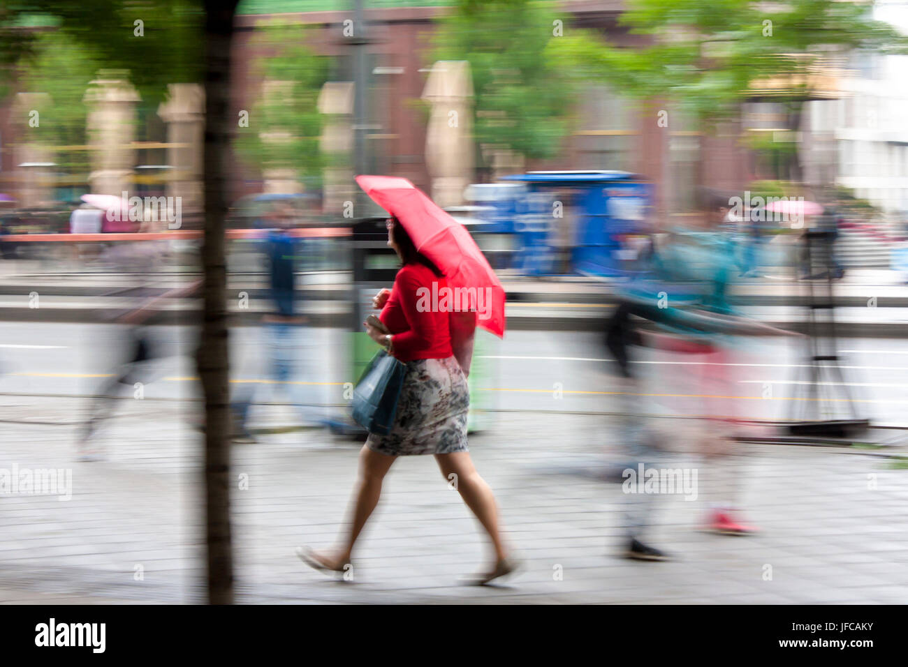 Belgrade, Serbia - May 5, 2017: Blurry woman under umbrella walking on the city street on a rainy spring day Stock Photo