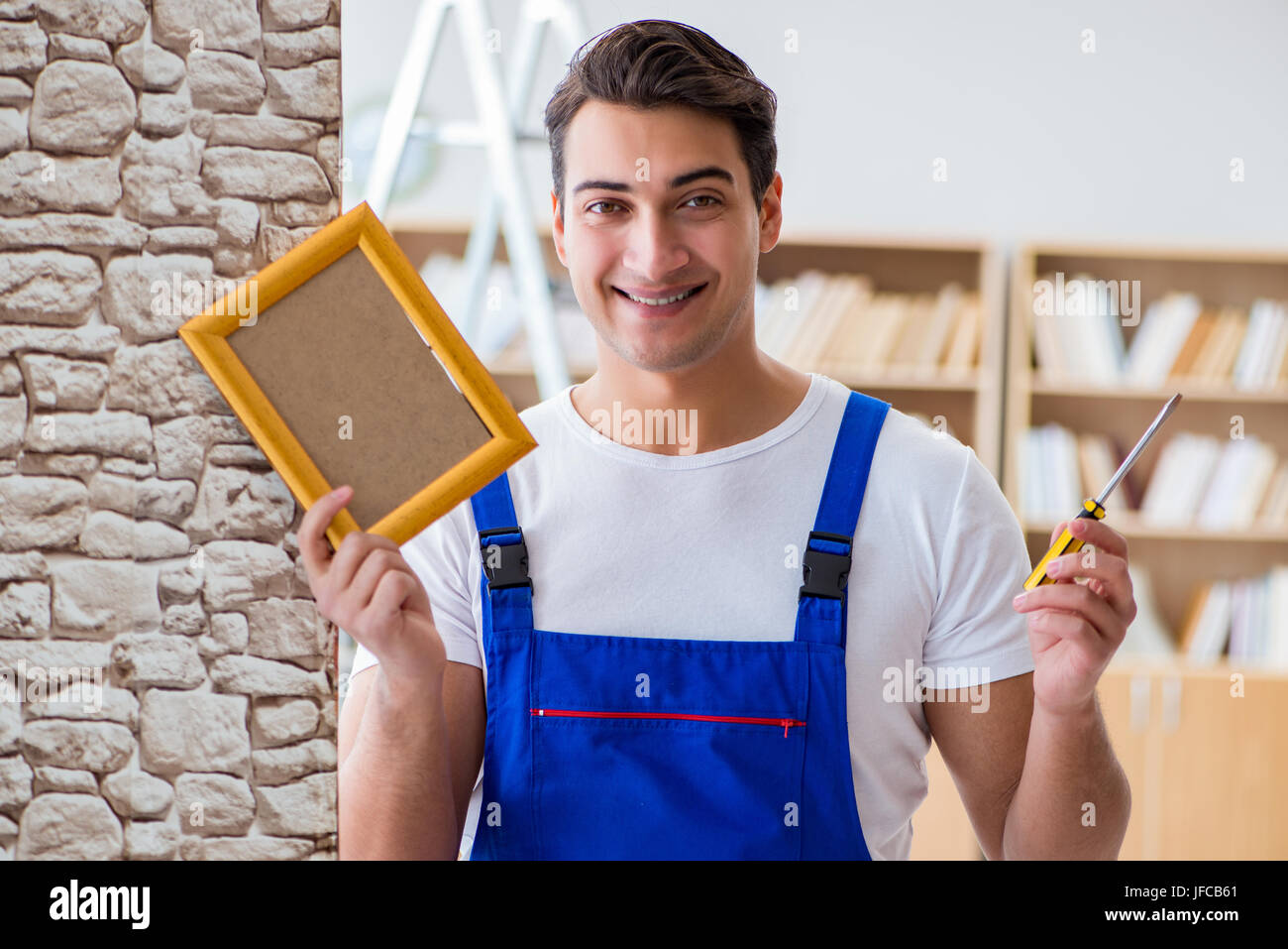 Repairman putting picture frame onto wall Stock Photo Alamy