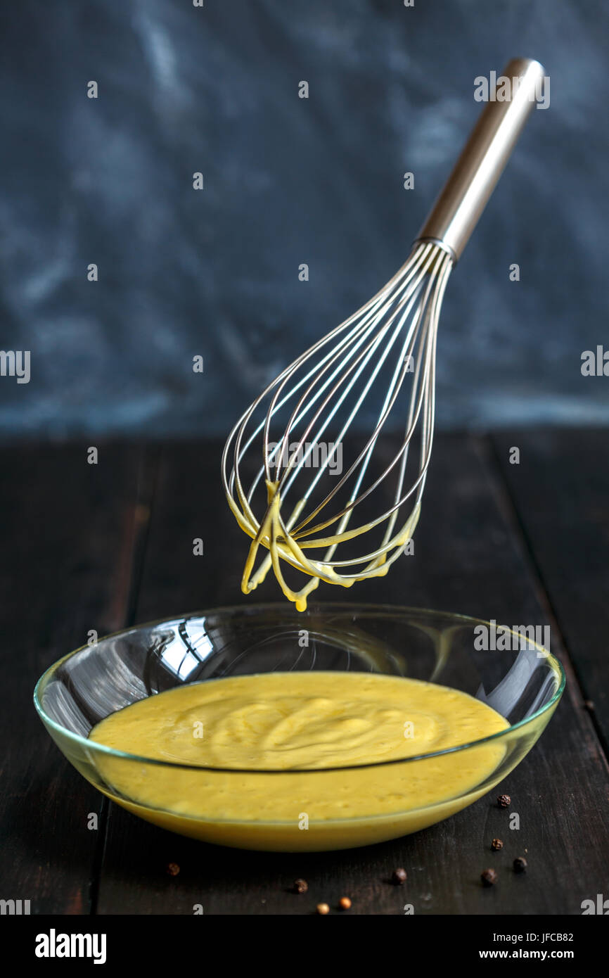 Homemade mayonnaise sauce in a glass bowl and metal whisk Stock Photo