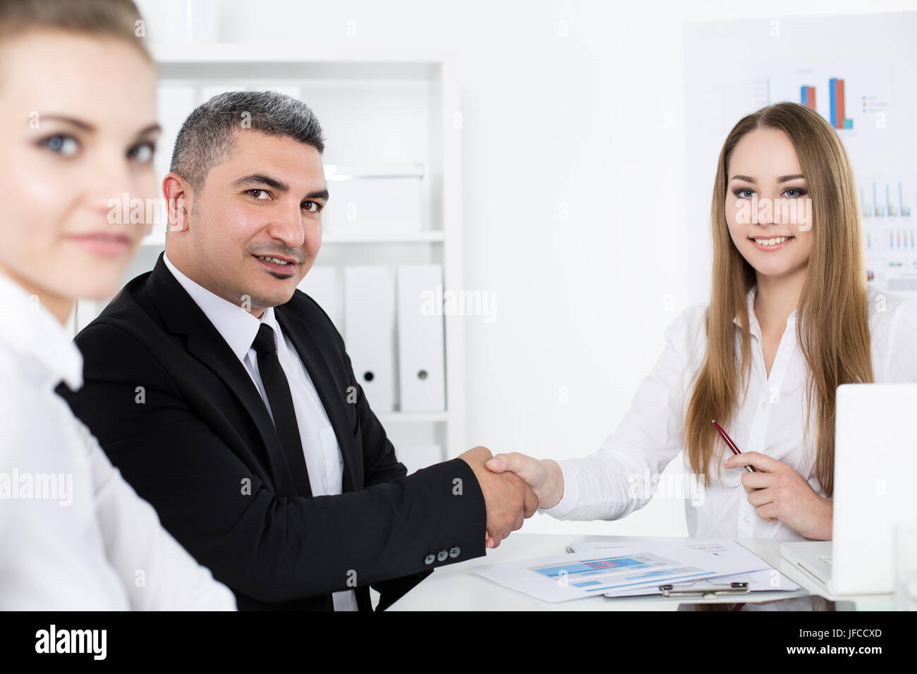 Businessman in suit shaking young business woman's hand. Partners made deal and sealed it with handclasp. Formal greeting gesture Stock Photo