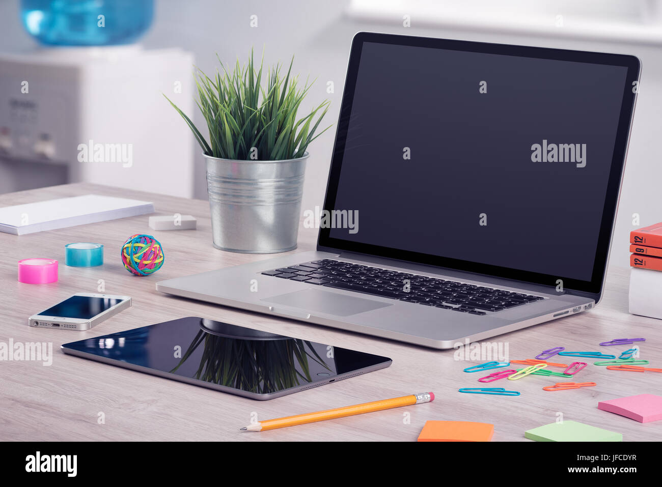 Modern office workplace with laptop computer mockup, tablet pc and smartphone on the office desk. There is a laptop, tablet computer, smartphone on th Stock Photo