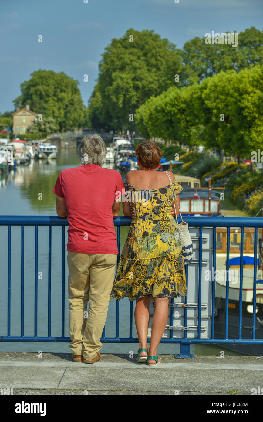 Rear view shot of a couple looking over the Garonne river canal in Moissac, Occitanie, France. Stock Photo