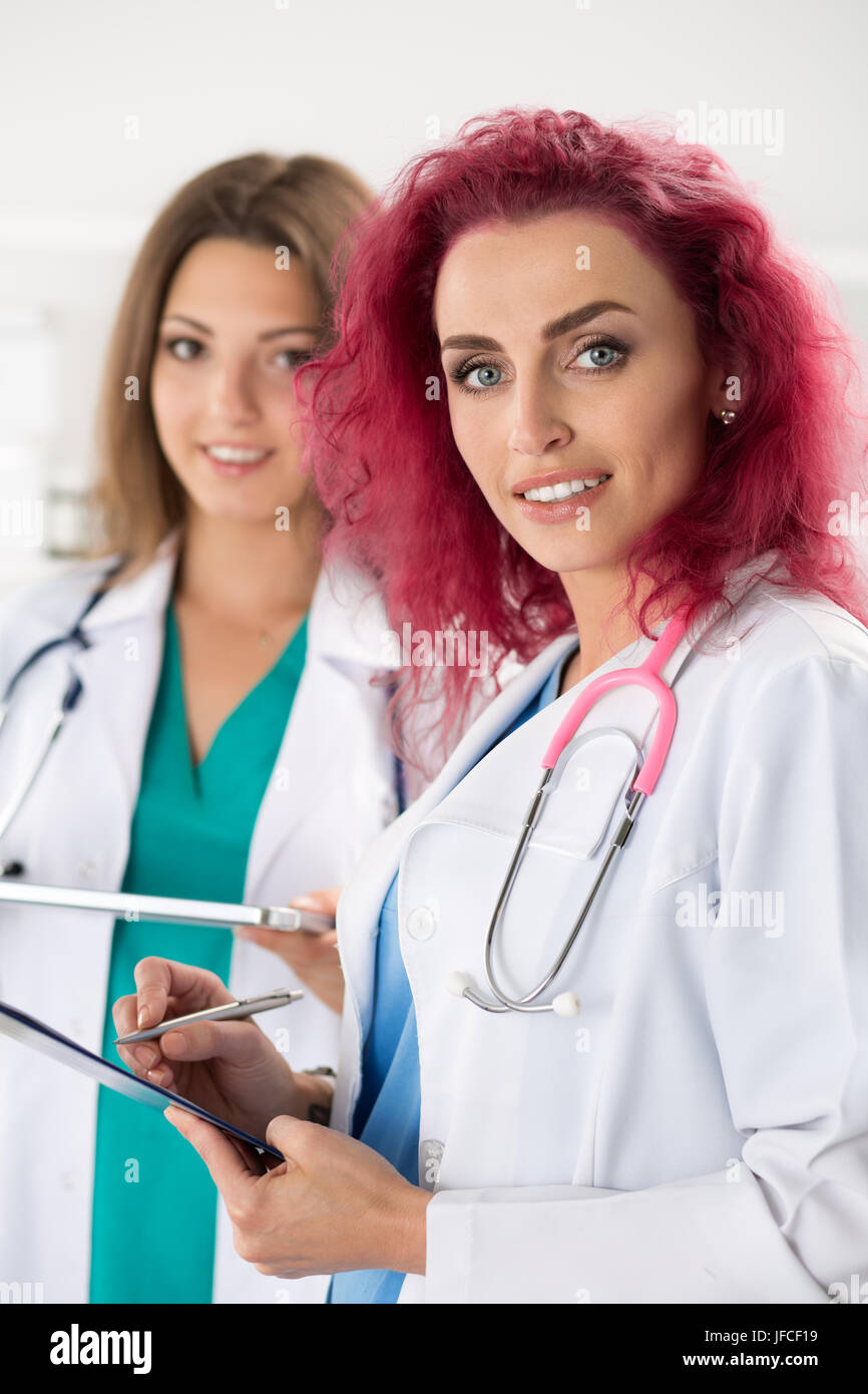 Portrait of two female doctors standing with clipboard and tablet ready to work. Health care, medical service or education and teamwork concept. Stock Photo