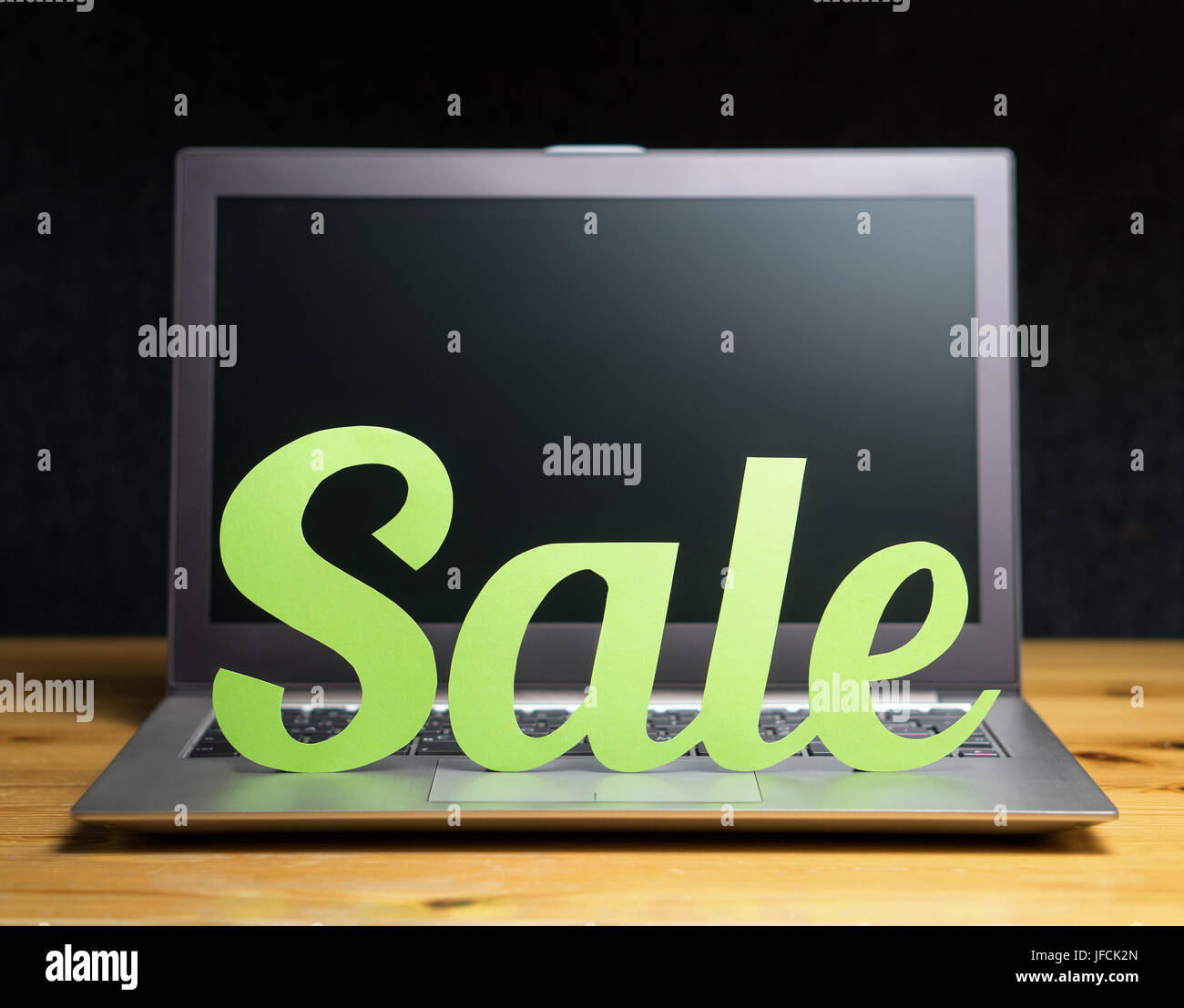 Online shopping and e-commerce concept. Laptop computer with sale letters cut from cardboard paper. Discount and bargain prices on internet store. Stock Photo