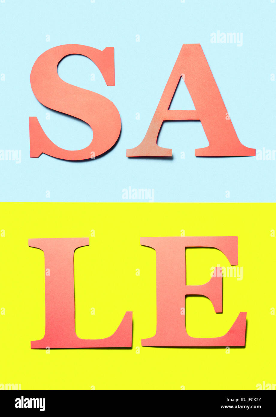 Vertical sale sign. Red orange letters cut from cardboard paper on light blue and yellow background. Colourful craft banner for marketing a special. Stock Photo