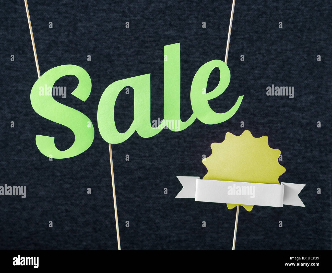 Fun summer sale design for promo. Hanging green letters and yellow badge with ribbon cut from cardboard paper on wooden stick. Fresh and fun marketing Stock Photo