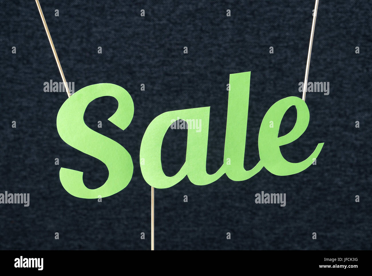 Sale text hanging from ceiling by wooden stick. Vibrant summer design for marketing in website or social media. Green letters cut from cardboard. Stock Photo
