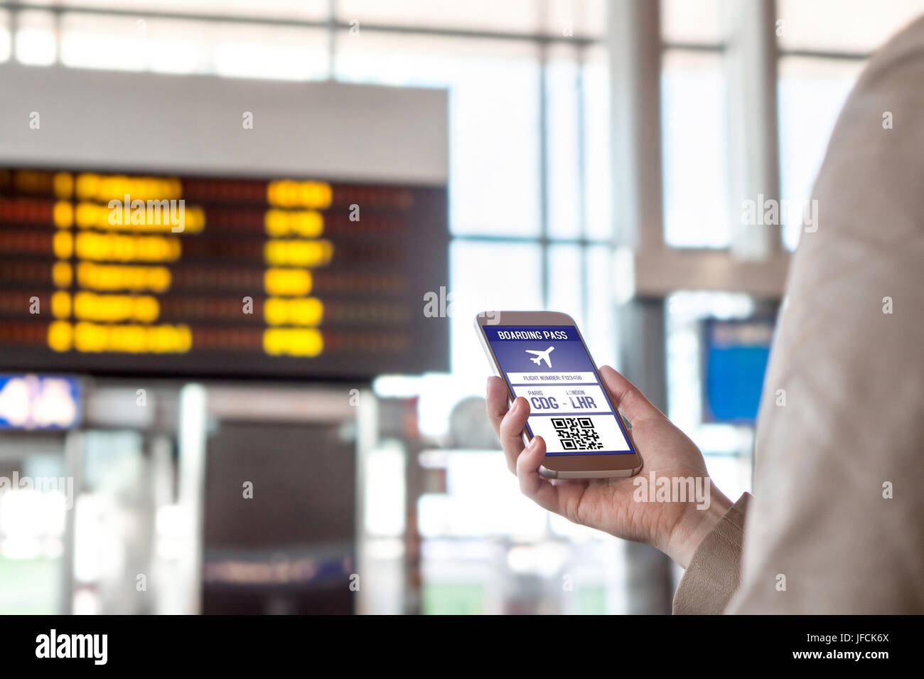 Boarding pass in smartphone. Woman holding phone in airport with mobile ticket on sceen. Modern travelling technology and easy access to aeroplane. Stock Photo