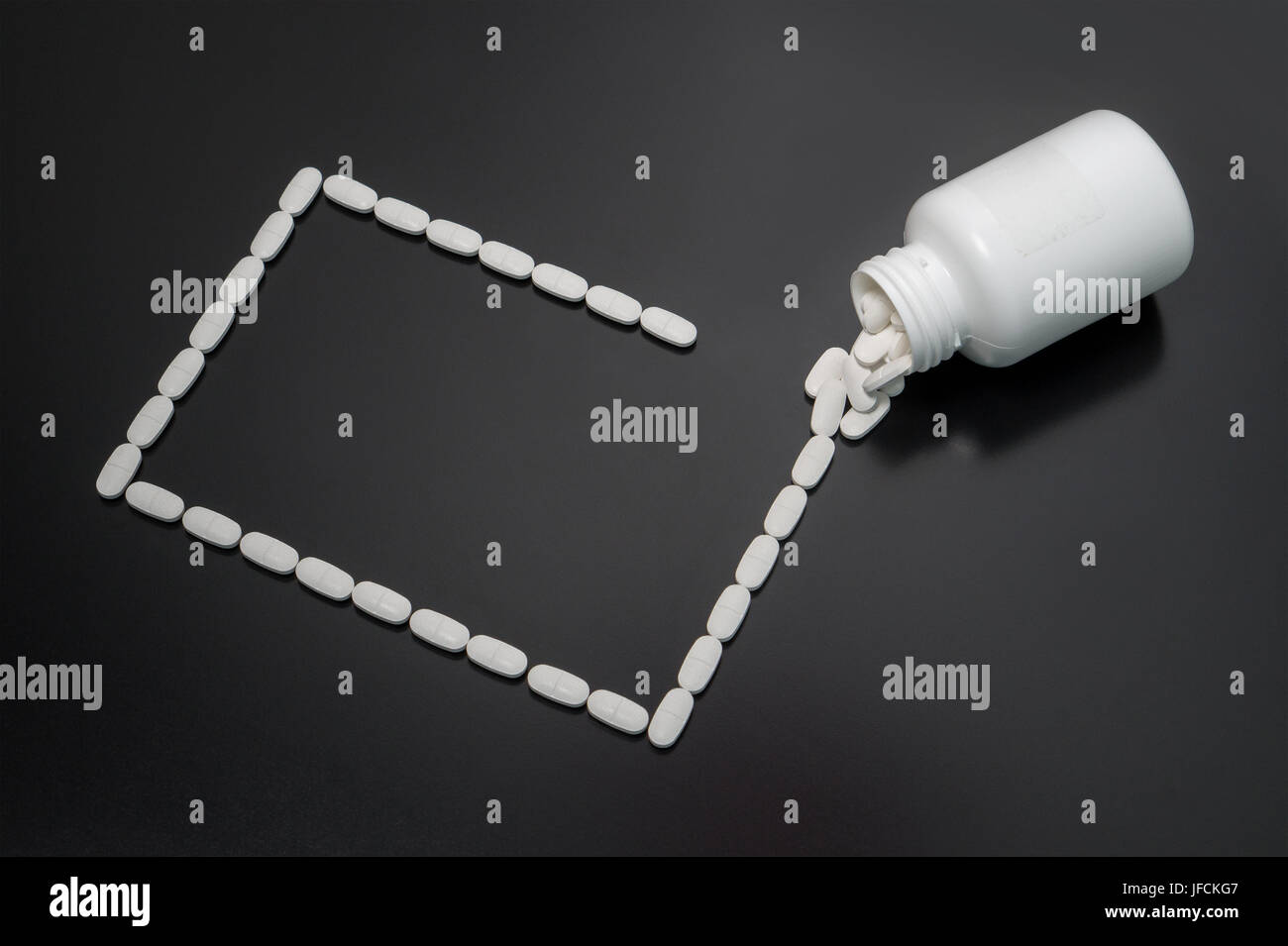 Pills spilled on table from bottle forming a rectangle. Innovative background, basis or template for medical presentation. Stock Photo