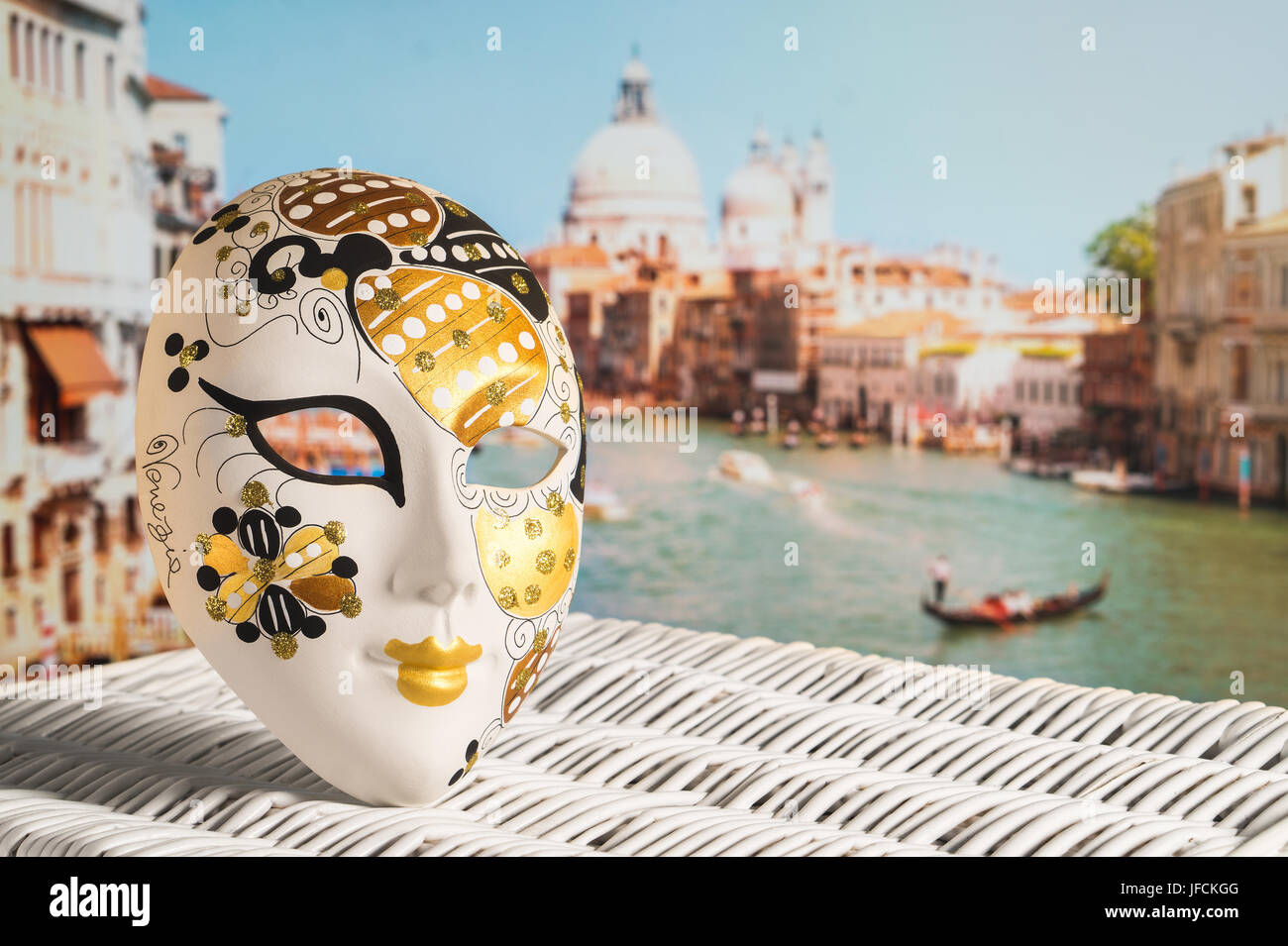 Venetian mask with Canal Grande and Santa Maria della Salute church in the background. Traditional souvenir and beautiful view to the gondola. Stock Photo