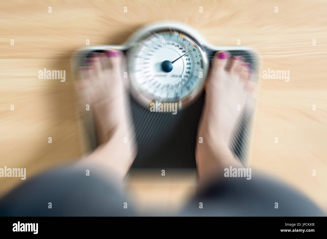 Top view to female feet on scale with dramatic blur zoom effect. Stock Photo