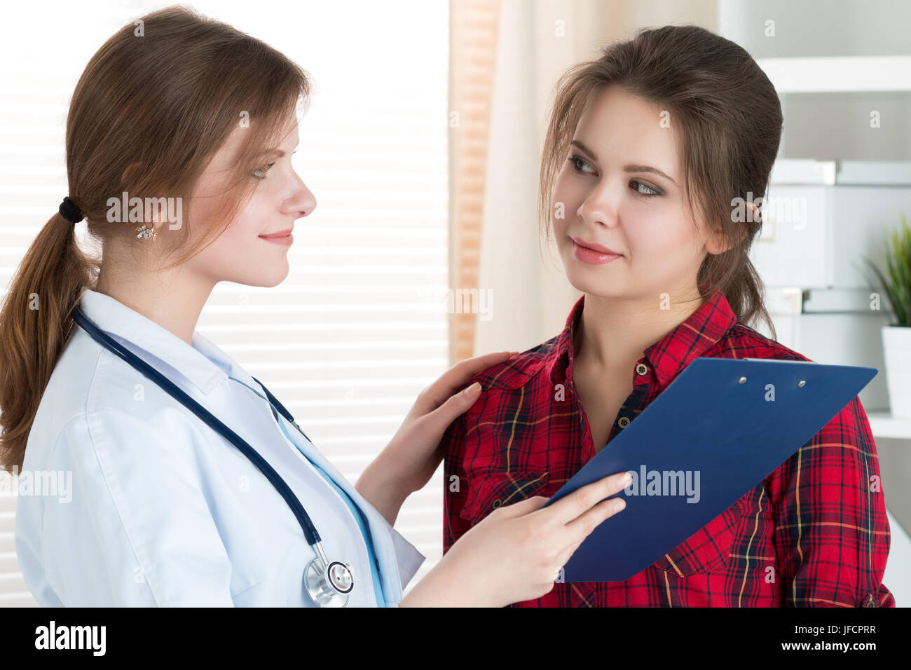 Friendly female doctor touching patient shoulder for encouragement, empathy, cheering and support after medical examination. Trust and ethics concept. Stock Photo