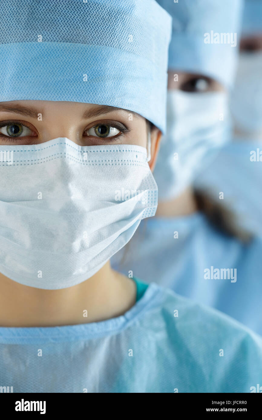 Close-up portrait of a female surgeon wearing surgical cap and mask in ...