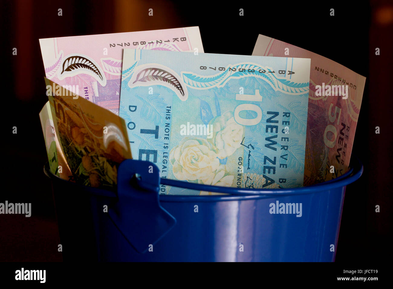 New Zealand dollars in a blue bucket Stock Photo