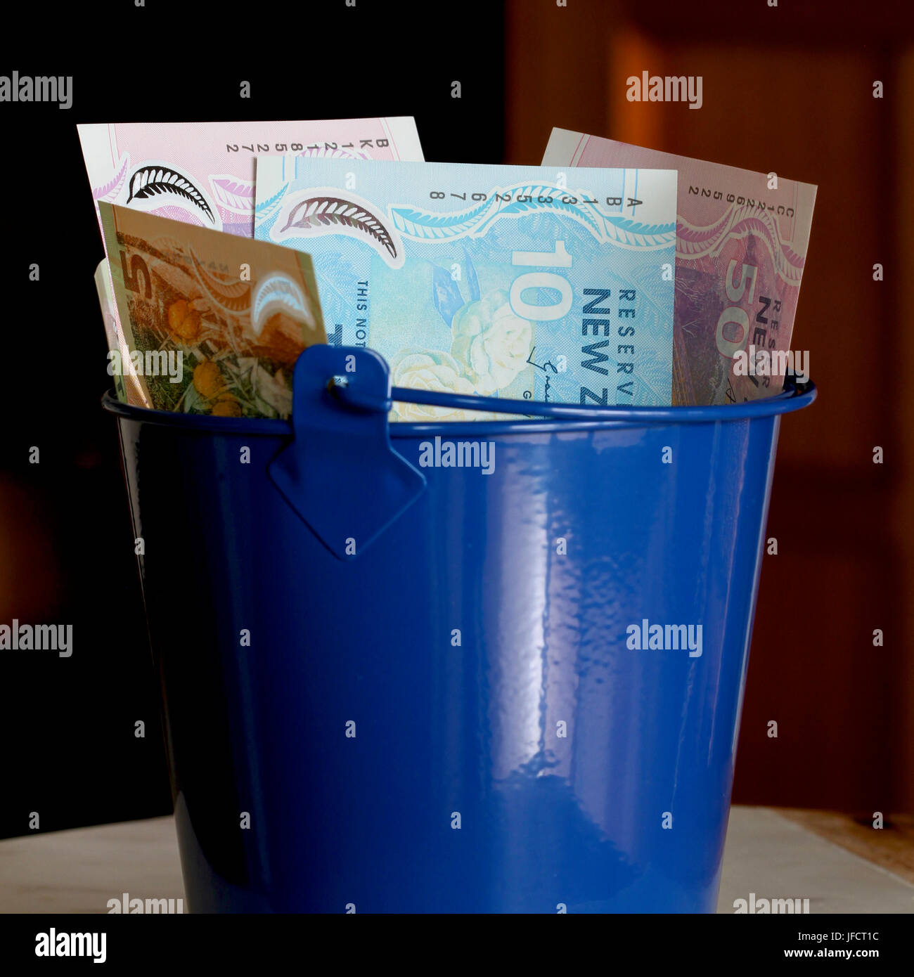 New Zealand dollars in a blue bucket Stock Photo