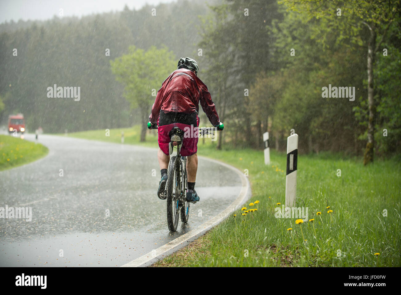 Man drives up on the bicycle in the flowing out rain an increase Stock Photo