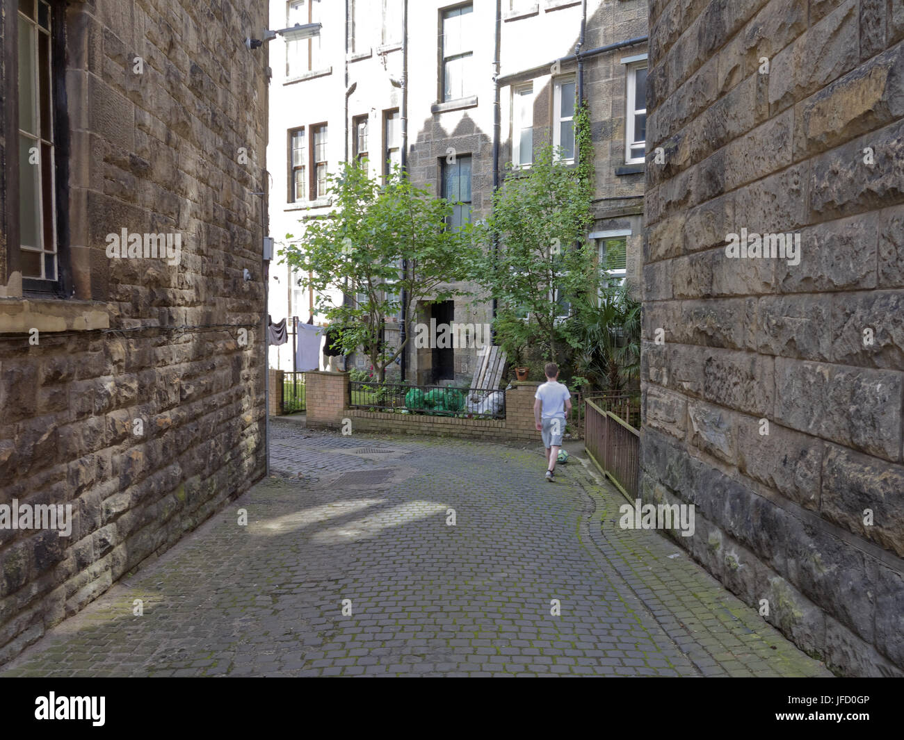 Glasgow tenements life background blond sandstone back court boy with football Stock Photo