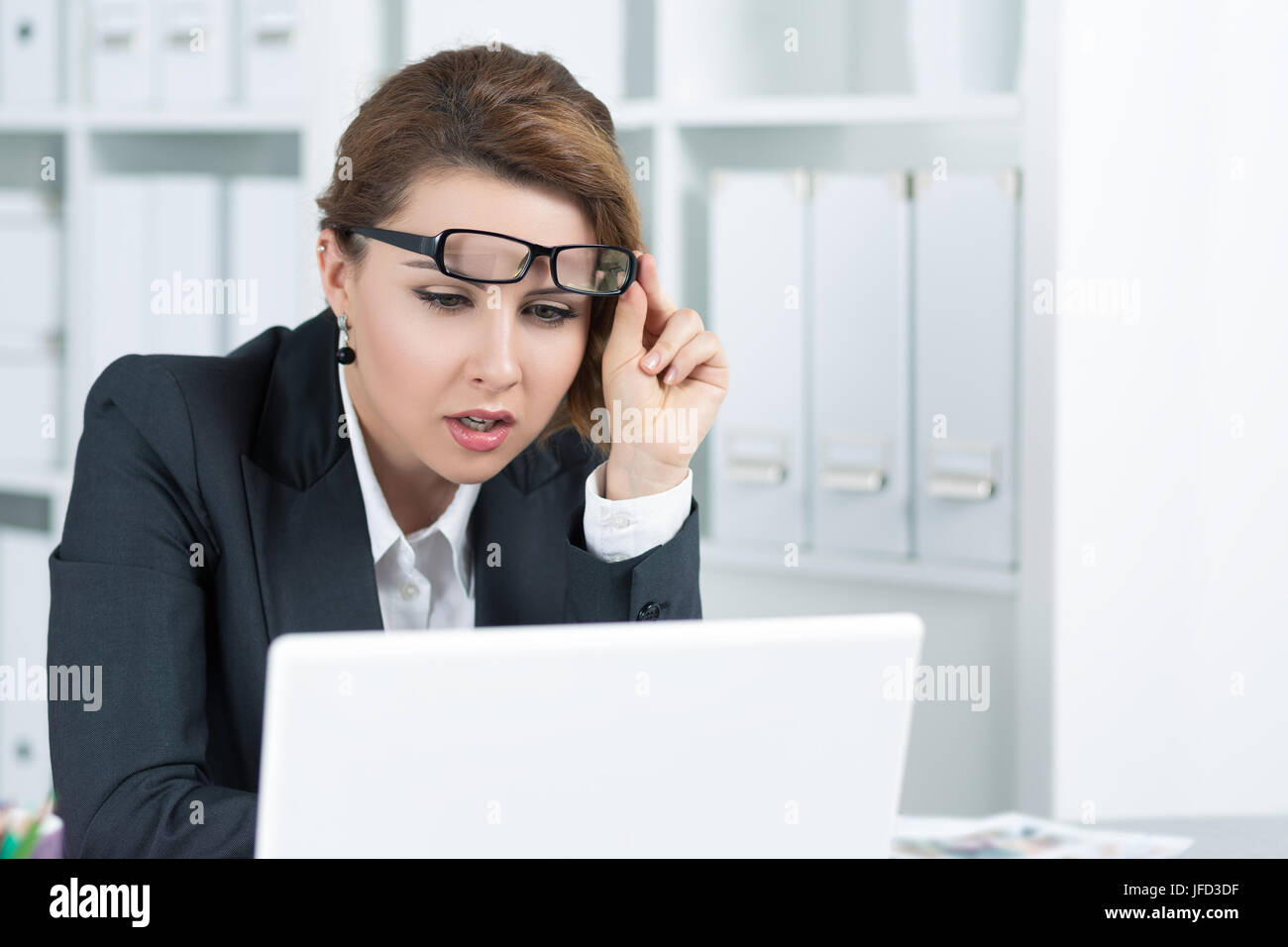Young business woman looking intently at laptop monitor seeing something unusual Stock Photo