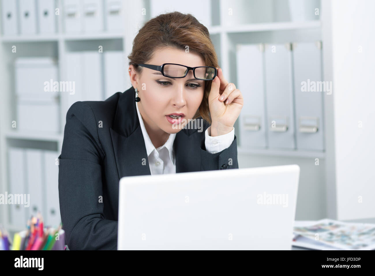 Young business woman looking intently at laptop monitor seeing something strange Stock Photo