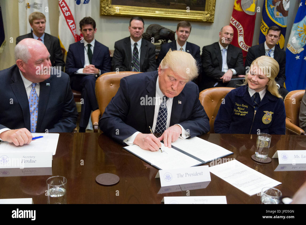 U.S. Secretary of Agriculture Sonny Perdue and Valerie Earley, Vice President of the National FFA Central Region, look on as President Donald Trump signs an Executive Order promoting Agriculture and Rural Prosperity in America in the Roosevelt Room of the White House in Washington, D.C., Tuesday, April 25, 2017. (Official White House Photo by Shealah Craighead) Stock Photo