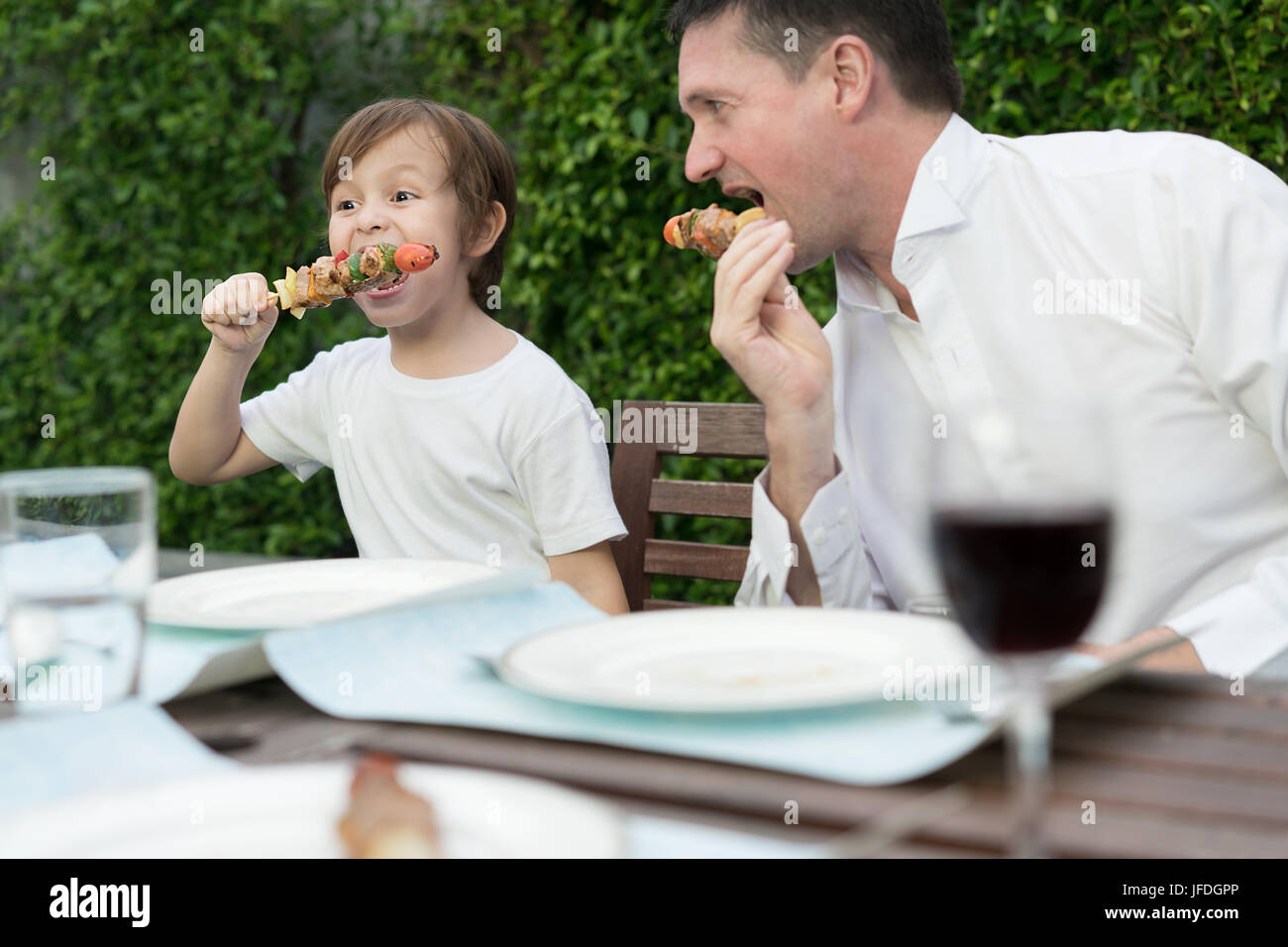 Father with little bcute boy eating barbecue in family lunch time at home. Stock Photo