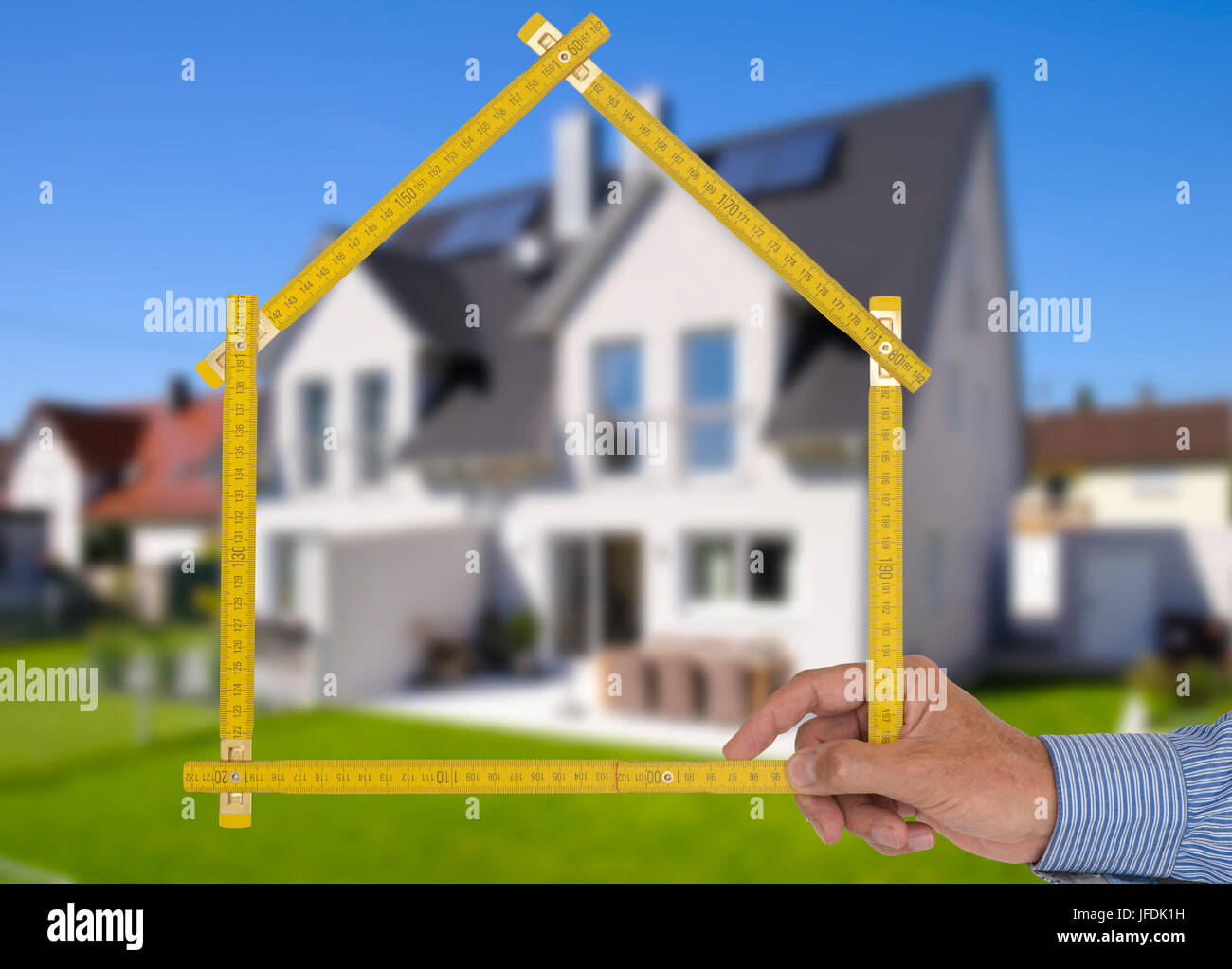 pocket ruler in hand of real estate agent in front of new house Stock Photo