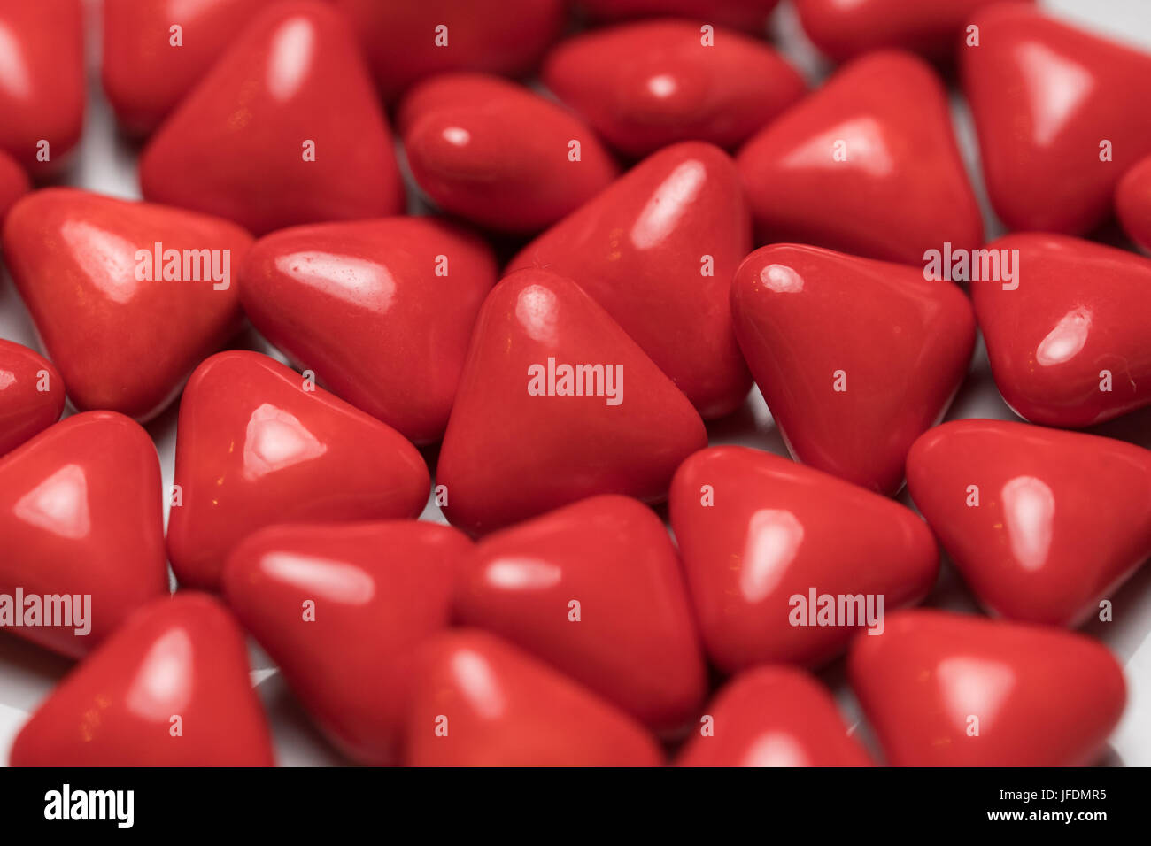 Closeup of red triangle pills looking like heart shaped candy isolated