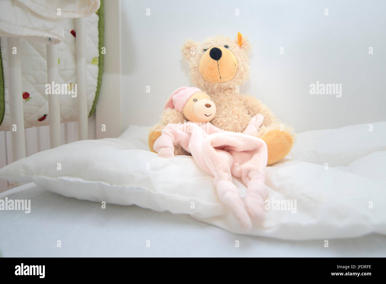 Two teddy bears in baby cott sitting on white pillow. Crib lovingly prepared by mother for the baby to be born Stock Photo